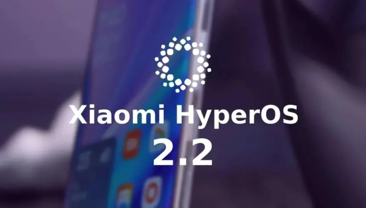 Close-up of a smartphone screen displaying the Xiaomi HyperOS logo, the text "Xiaomi HyperOS" stacked above the number "2.2", against a blurred purple background showing app icons.