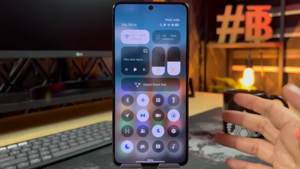 Xiaomi smartphone displaying the new HyperOS 3 control panel, with shortcuts to Wi-Fi, Bluetooth, airplane mode and media controls, in a desktop setup.