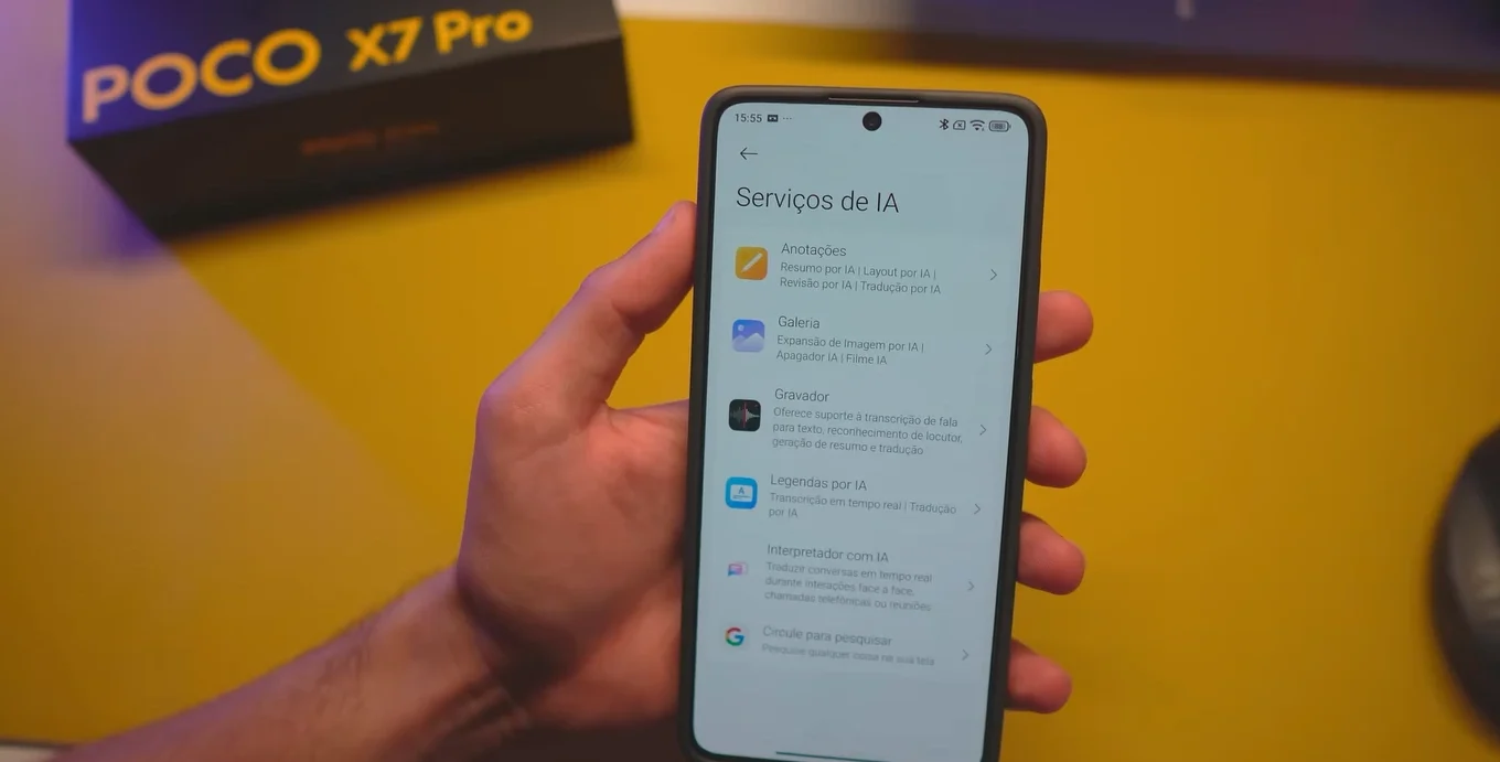 Hand holding a Xiaomi smartphone displaying the list of HyperOS 2.2's "AI Services", with features such as Notes, Gallery and Recorder.