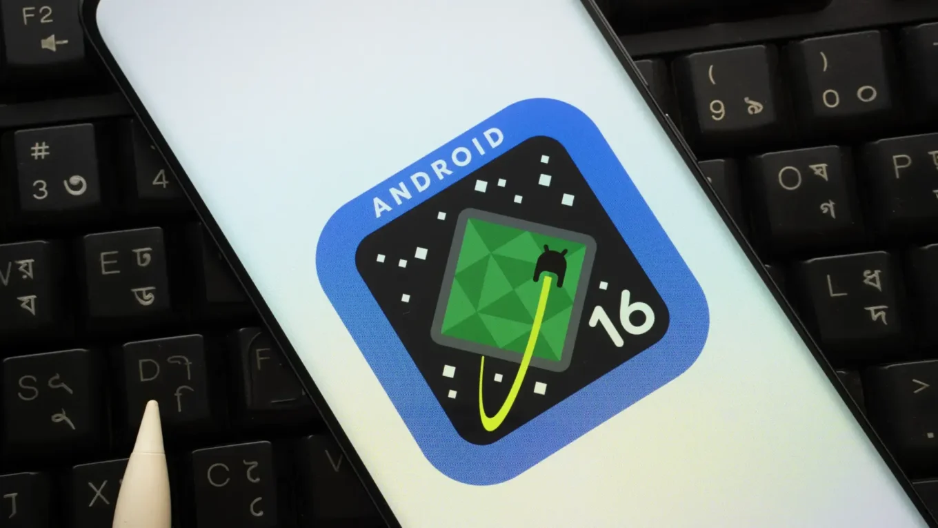 Smartphone displaying the Android 16 logo on the screen, with a stylized icon of a green electrical outlet on a black starry background.