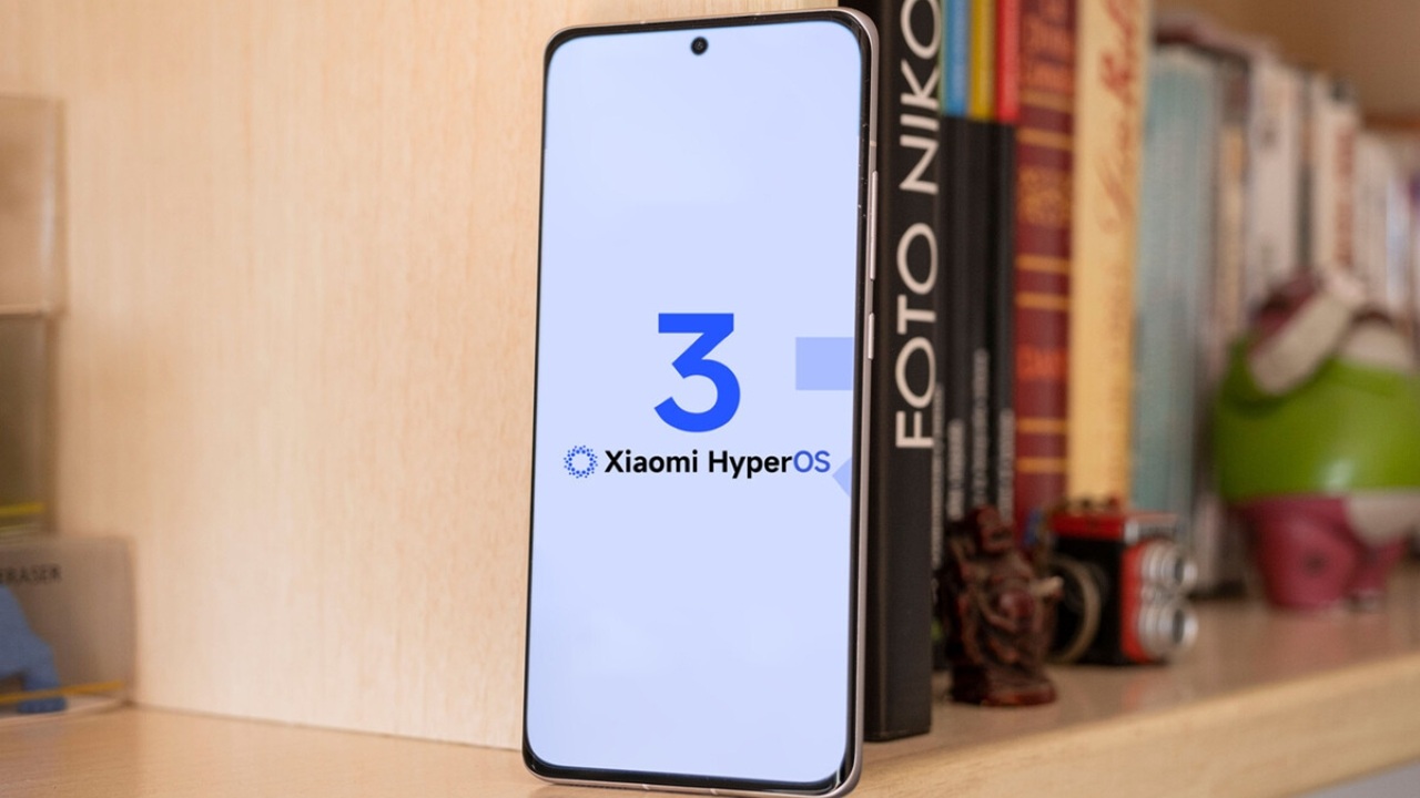 A Xiaomi smartphone positioned vertically on a shelf, displaying the official HyperOS 3 Global operating system logo on its screen with a large blue number 3 highlighted.